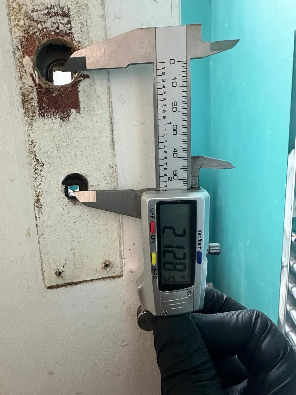 Digital caliper measuring lock holes in a door plate