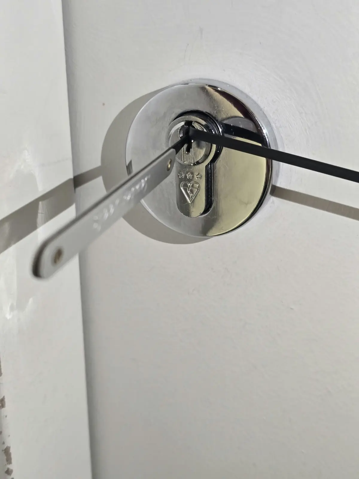 Two slim metal picks inserted through a circular chrome escutcheon