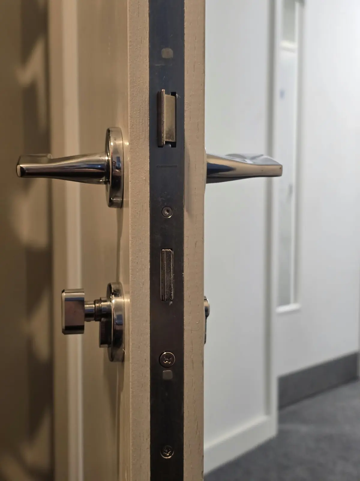 Chrome lever handles, thumb turn and a long latch plate seen edge-on
